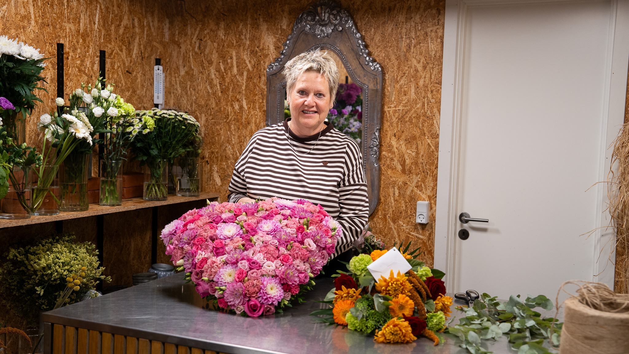 Jette fra Hyldebo Blomster med et stort lyserødt hjerte af friske blomster i blomsterbutikken.