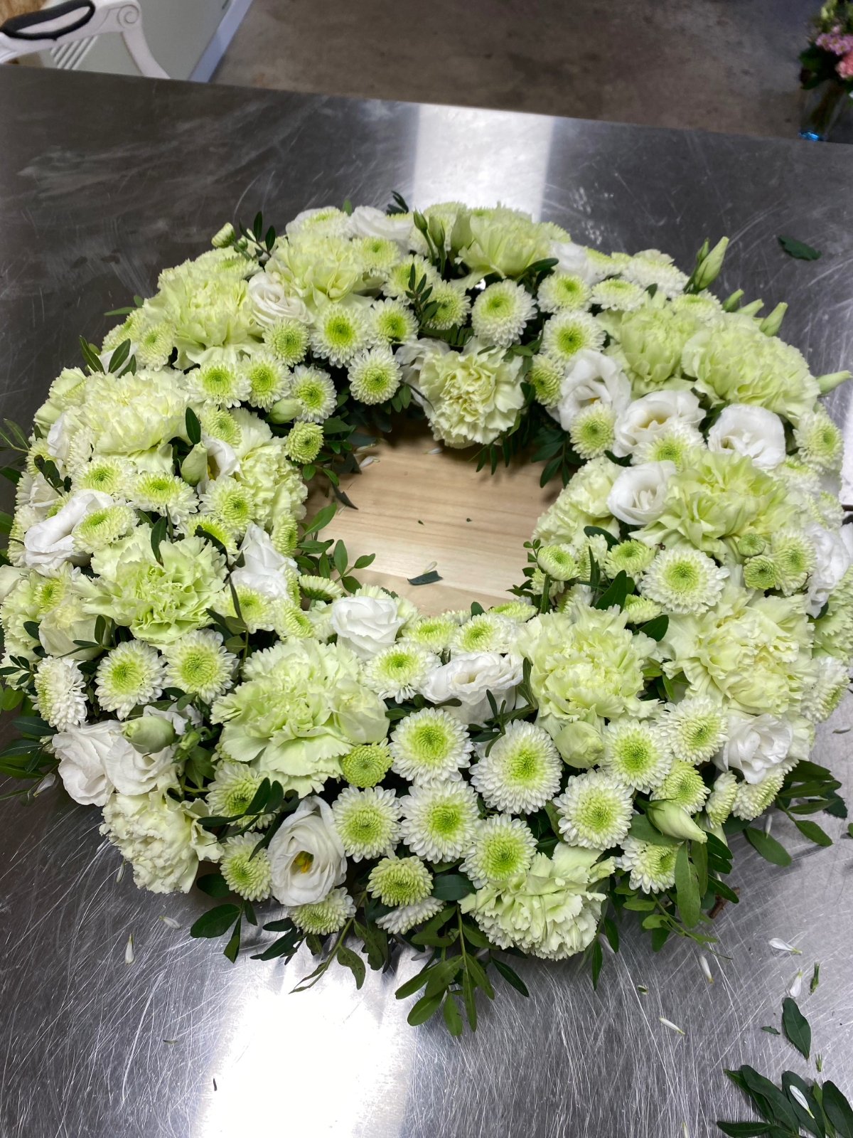 Hvid og lysegrøn blomsterkrans med krysantemum, nelliker og lisianthus.