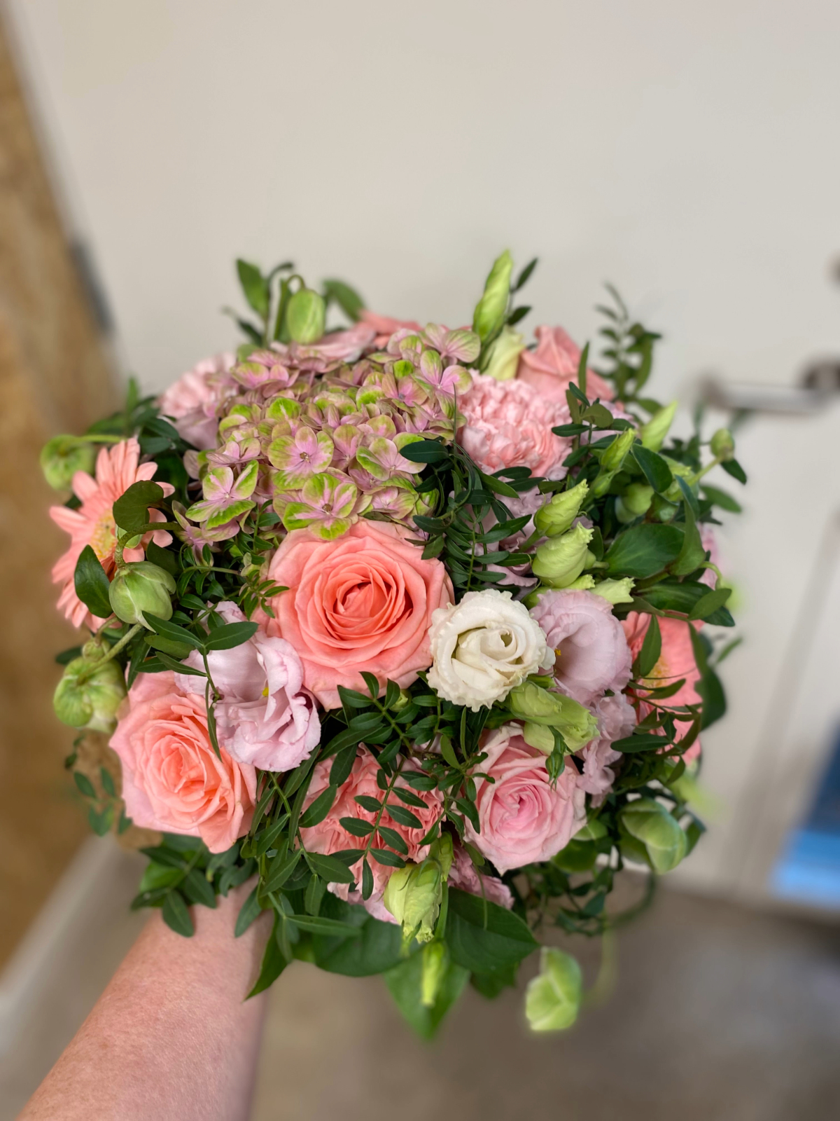 Rund buket med rosa roser og lyserøde blomster.