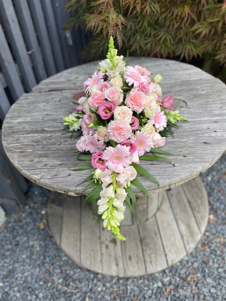 Lyserød båredekoration med roser, nelliker og gerbera i forskellige rosa nuancer.