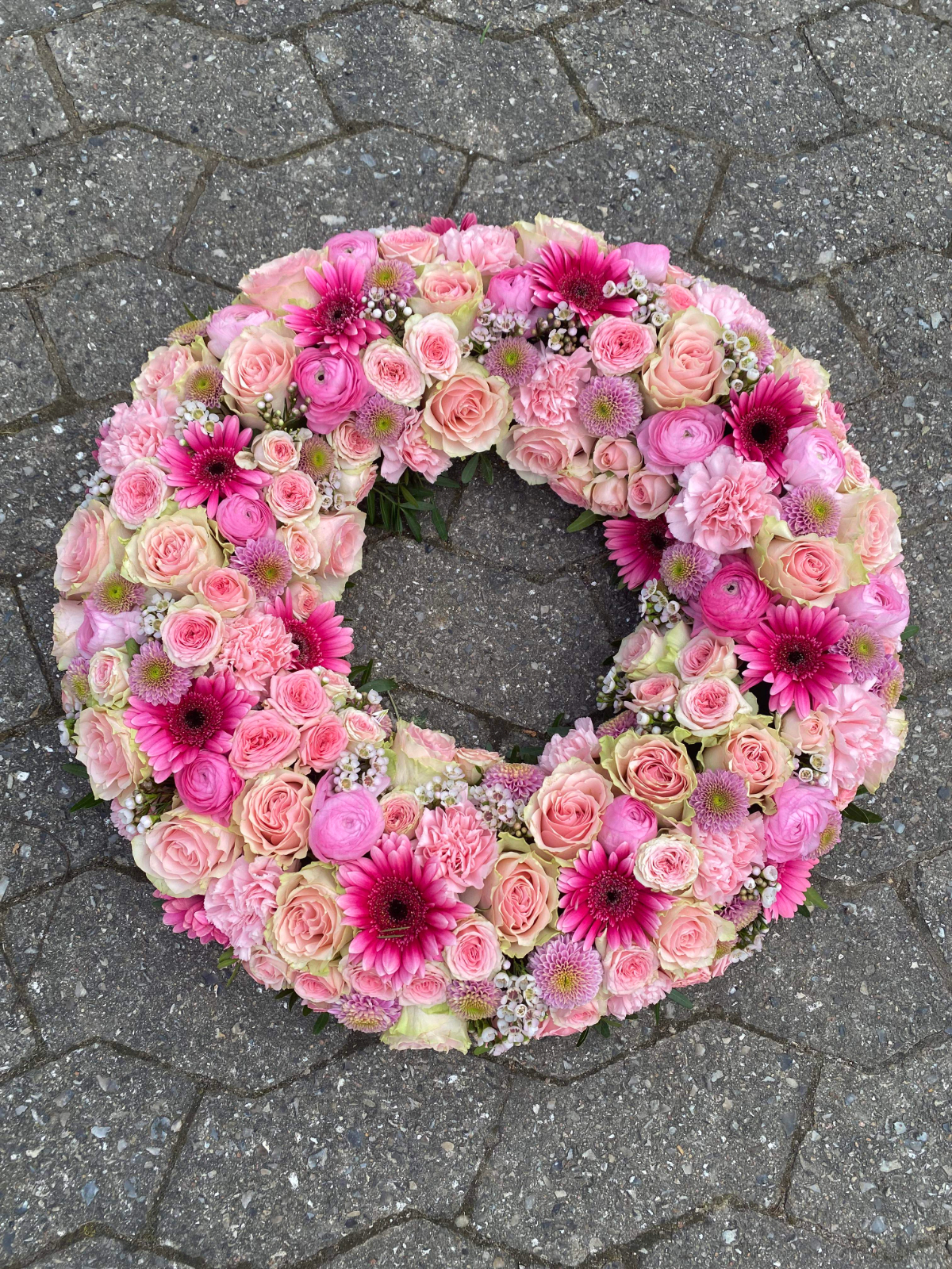 Rosa blomsterkrans med roser, gerbera, ranunkler og nelliker.
