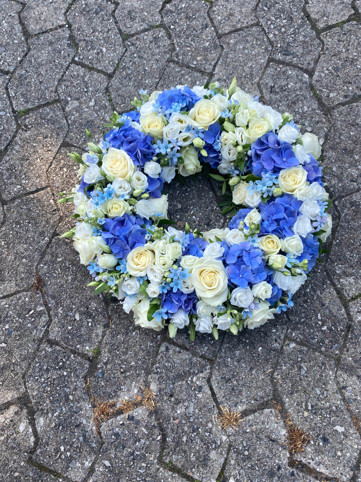 Blå og hvid blomsterkrans med hortensia, roser og lisianthus.