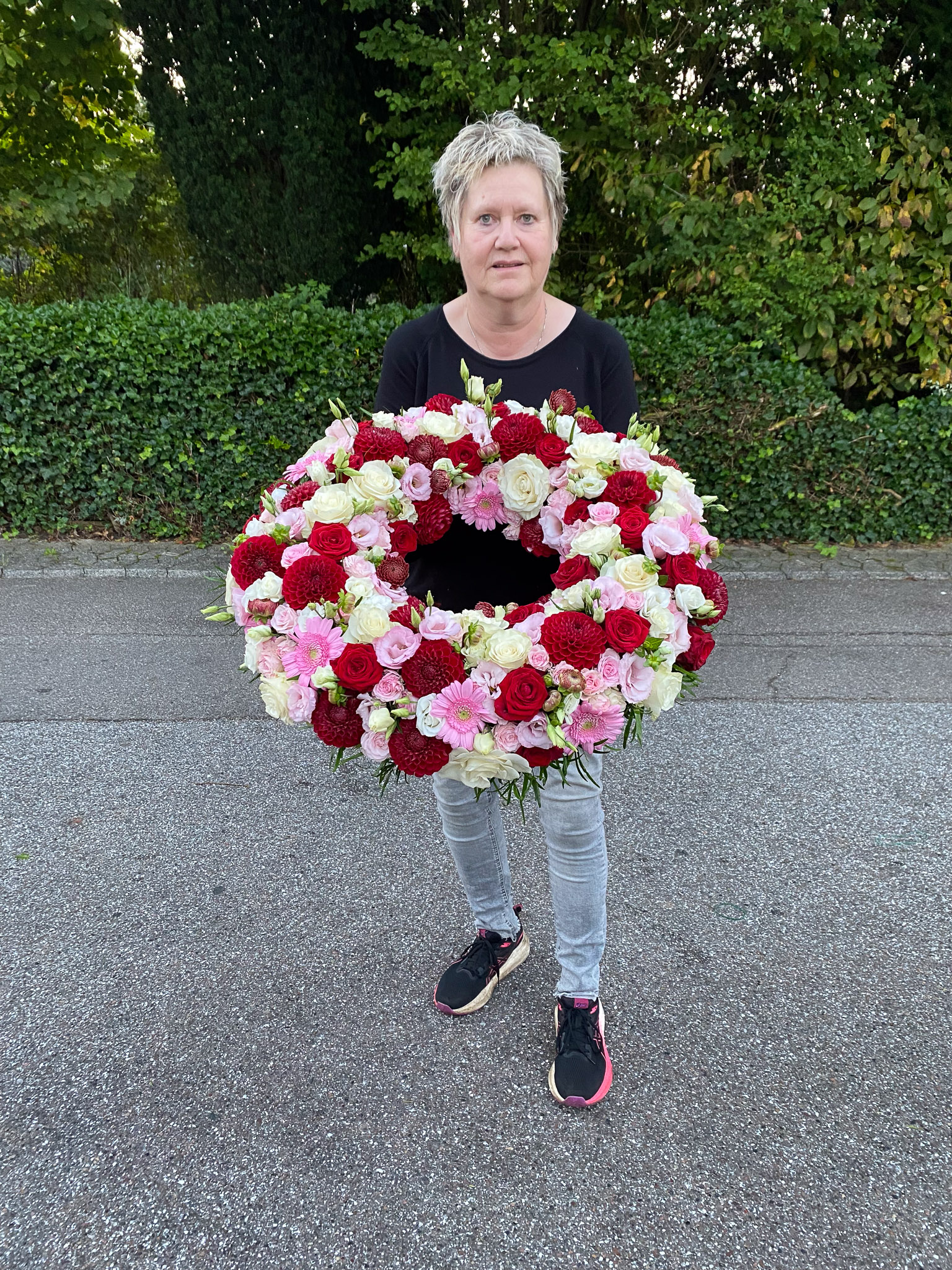 Cremefarvet krans holdt af blomsterhandler