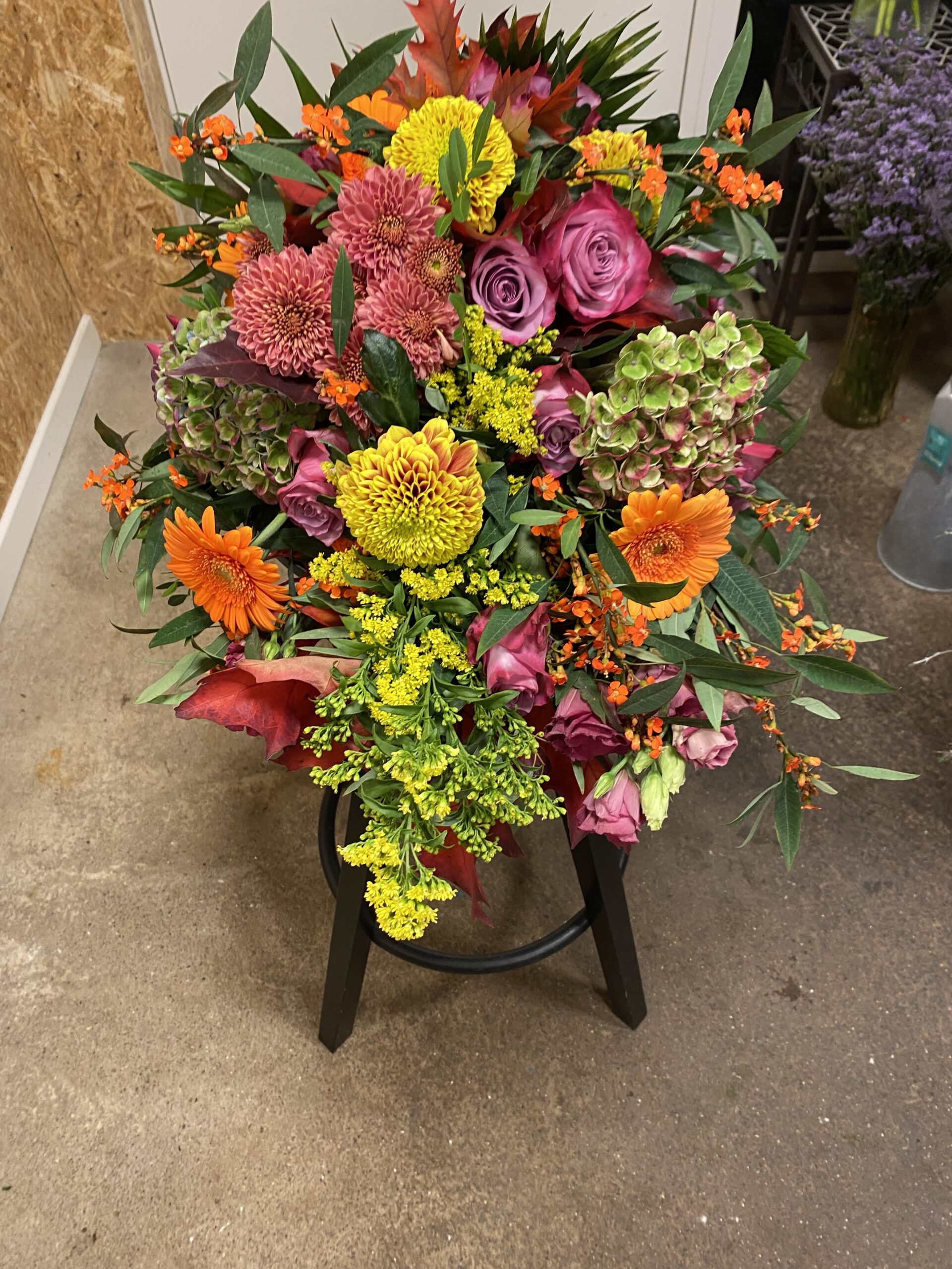 Farverig båredekoration med roser, gerbera, hortensia og efterårsfarvede blomster.