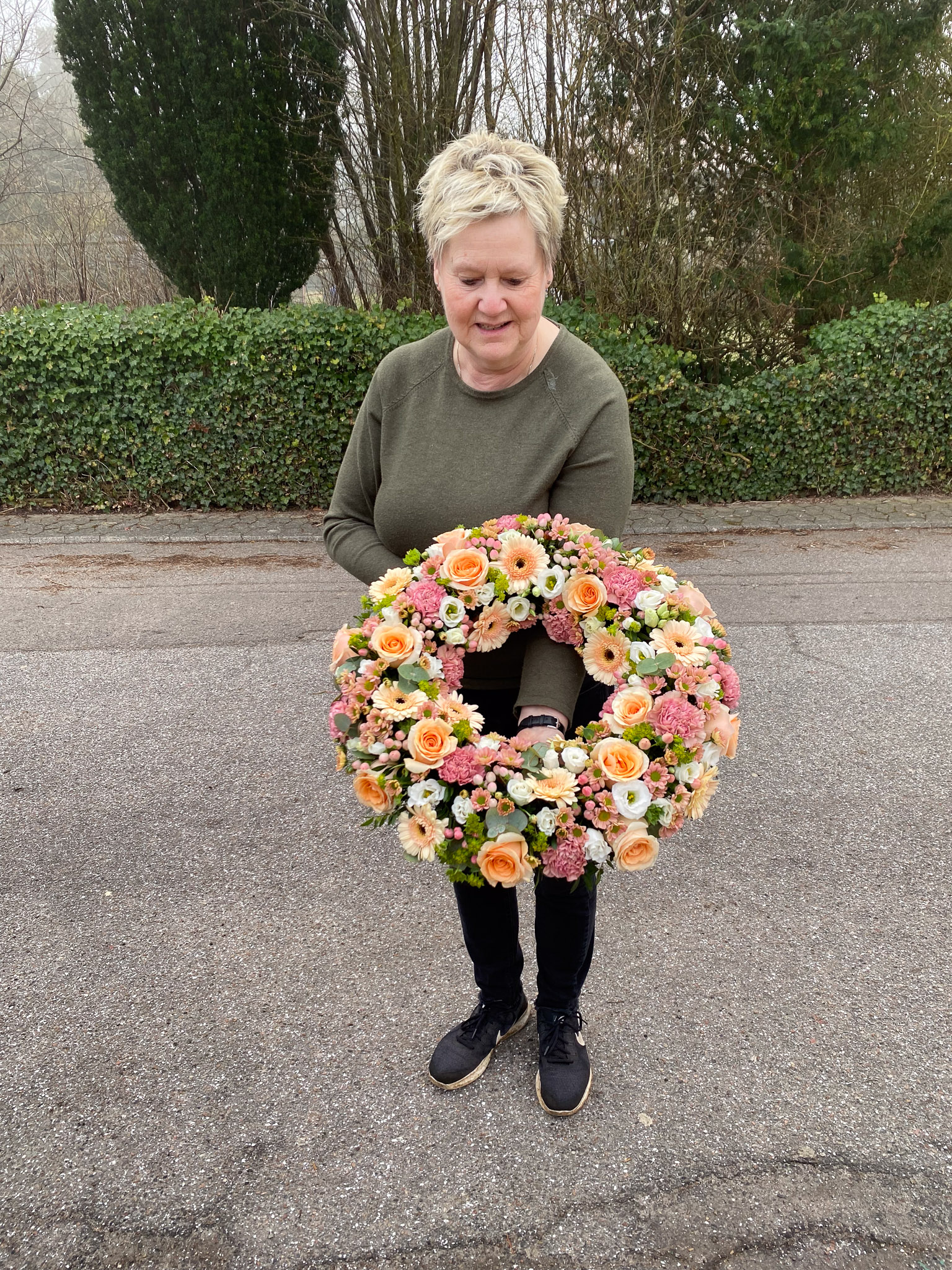 Hvid og cremefarvet krans holdt af blomsterhandler