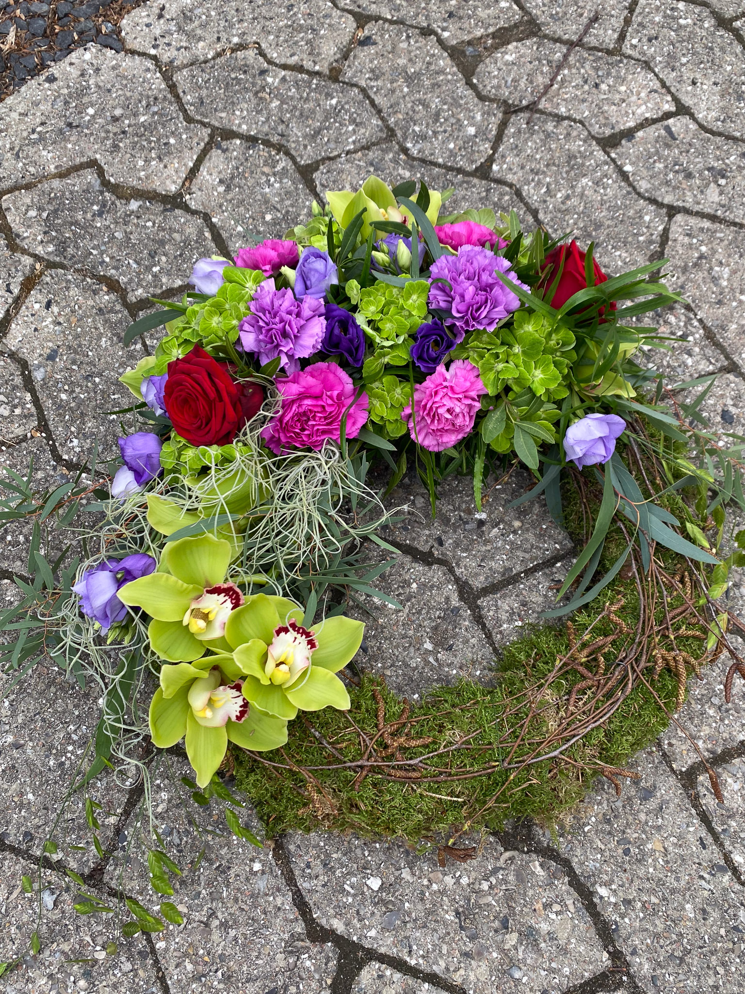 Mosekrans til begravelse med roser, lilla blomster og grønne orkideer