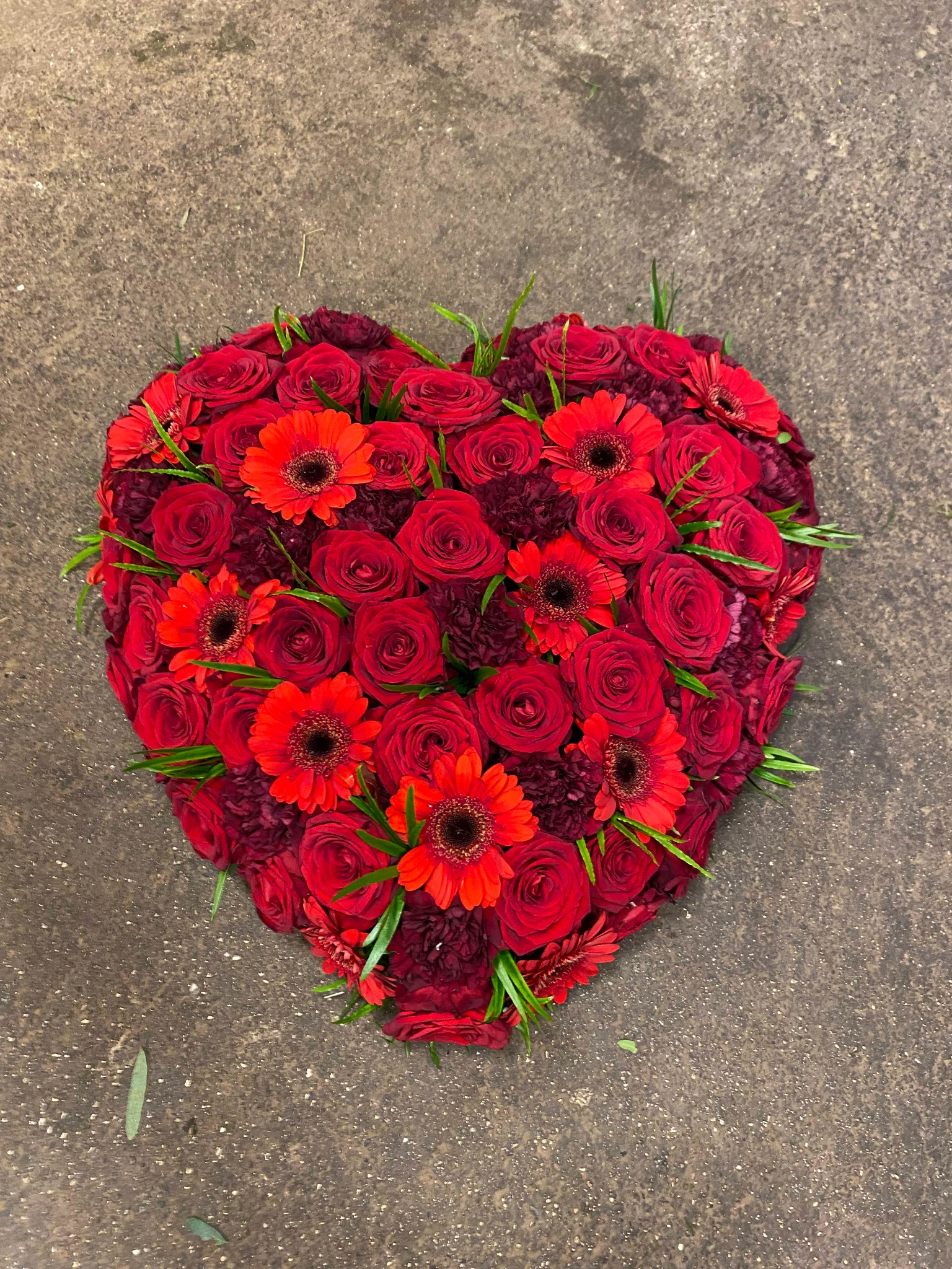 Fyldt rødt blomsterhjerte med roser og gerbera.