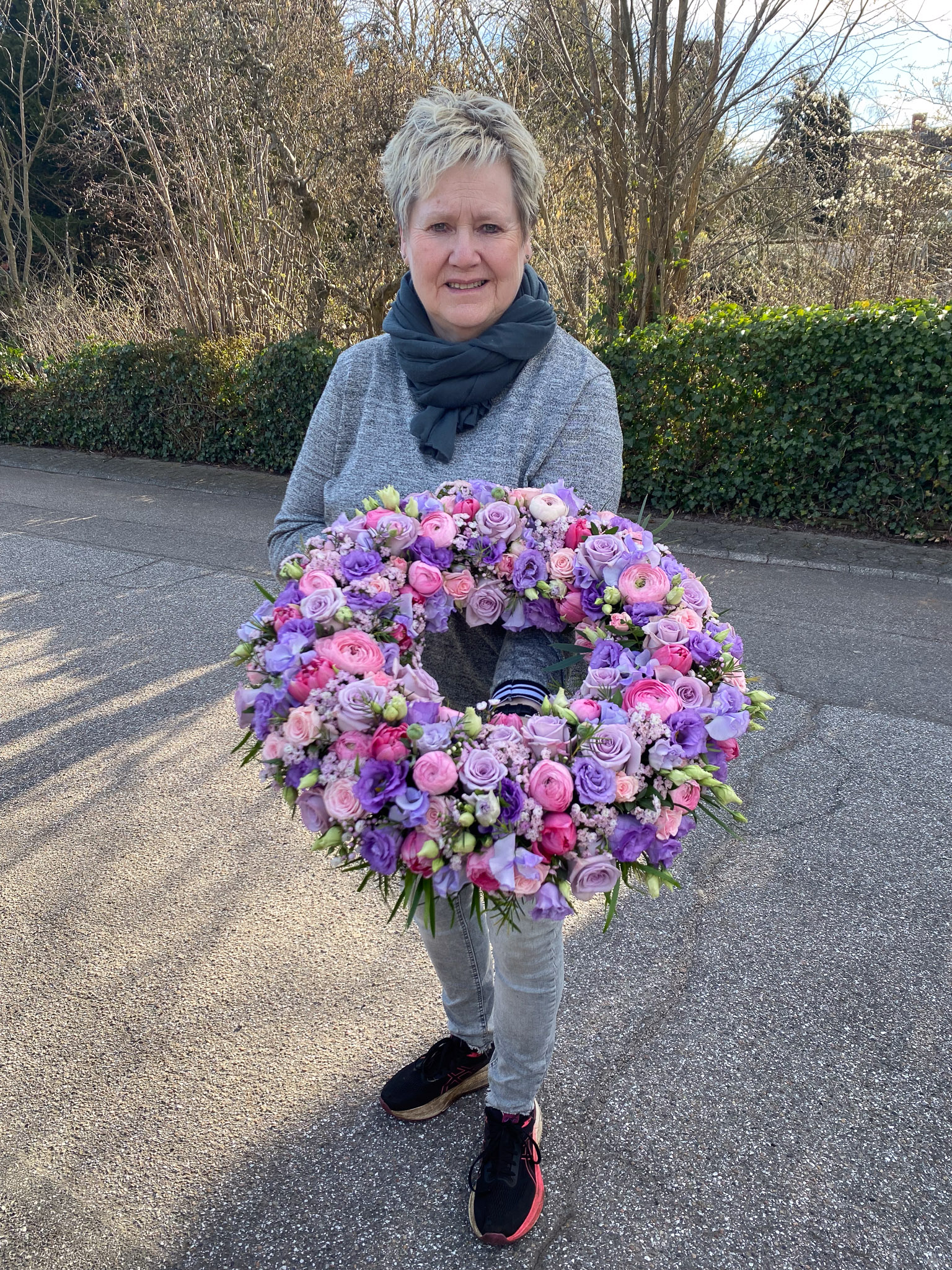 Lilla og flerfarvet krans holdt af blomsterhandler