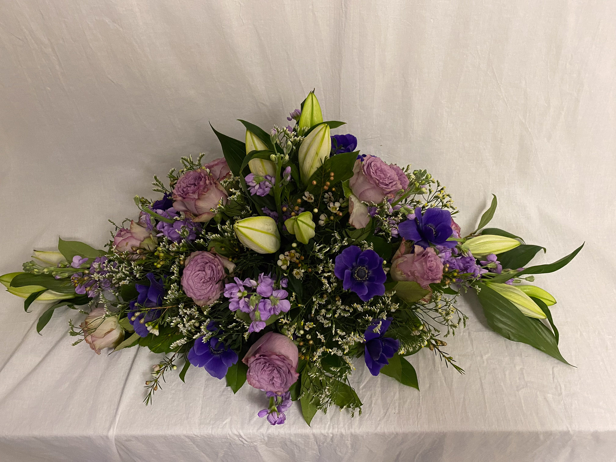 Lilla båredekoration med roser, anemoner, levkøj og hvide liljeknopper