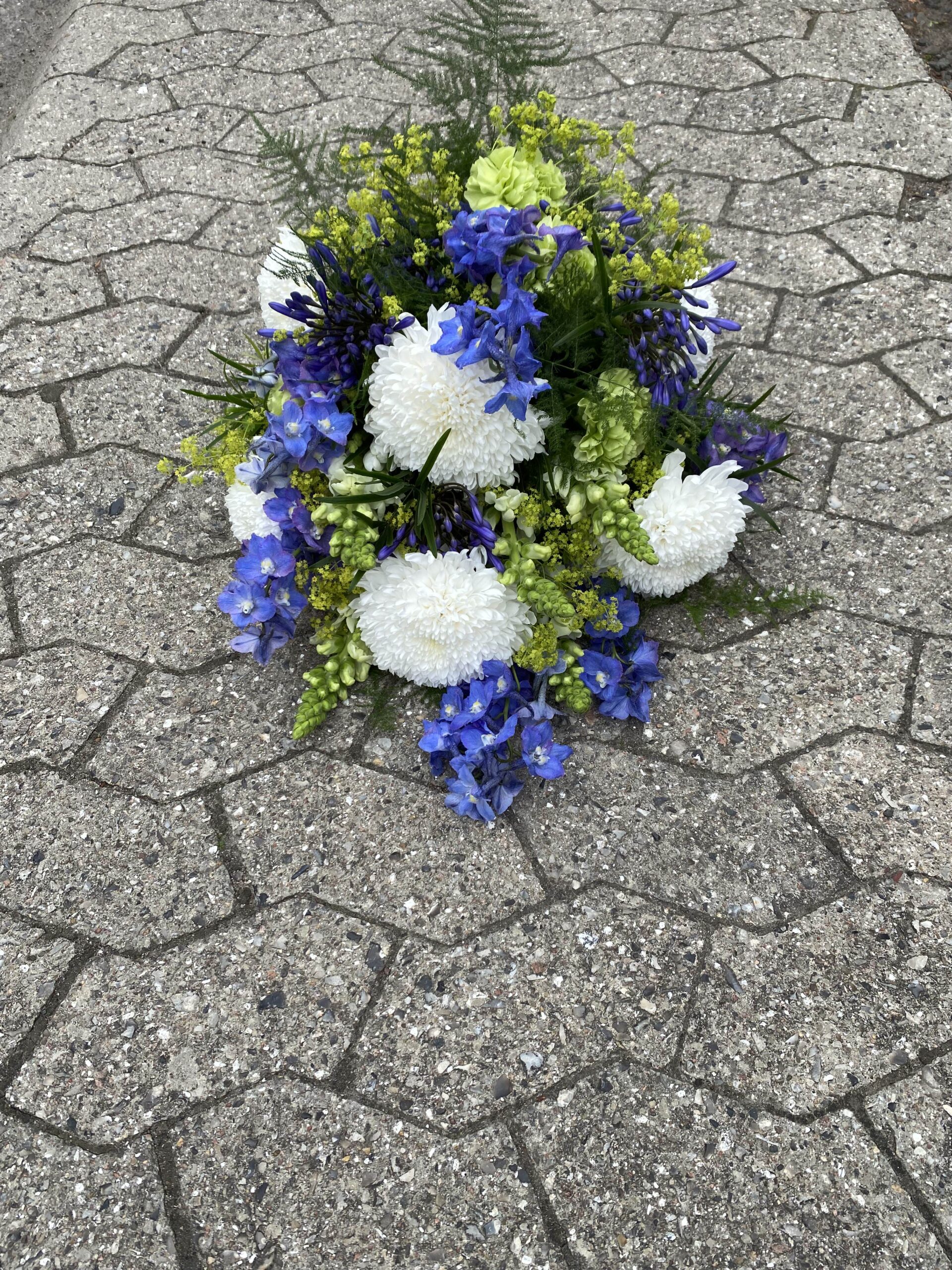 Blå og hvid blomsterdekoration med krysantemum og grønne detaljer.