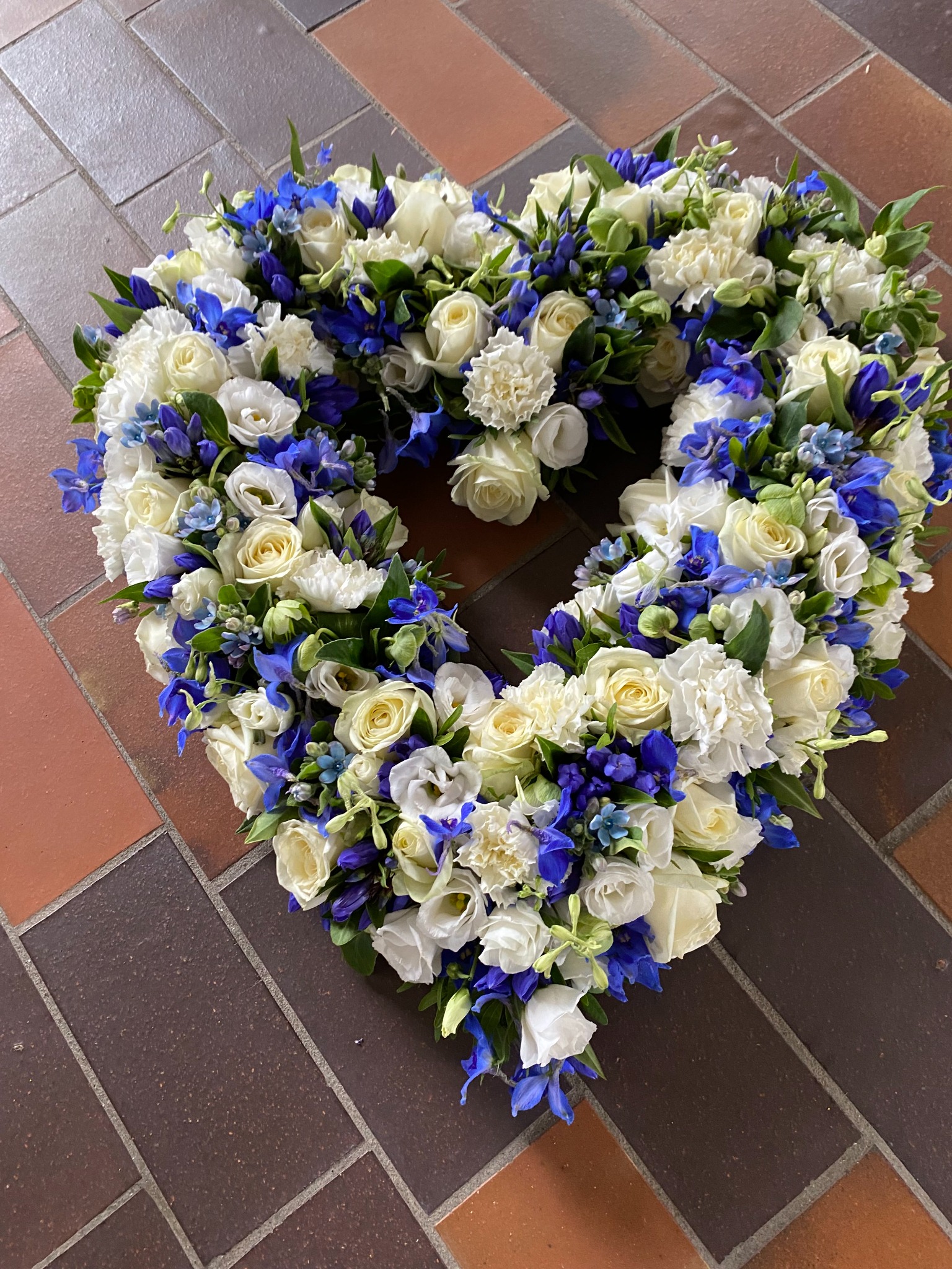 Farverigt blomsterhjerte med orange, gule, rosa og lilla blomster.
