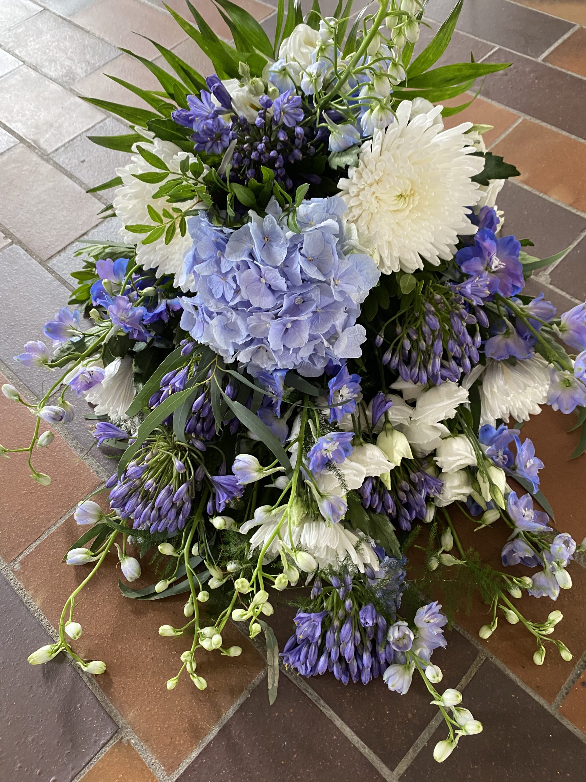 Blå og hvid båredekoration med hortensia, krysantemum og grønne blade.