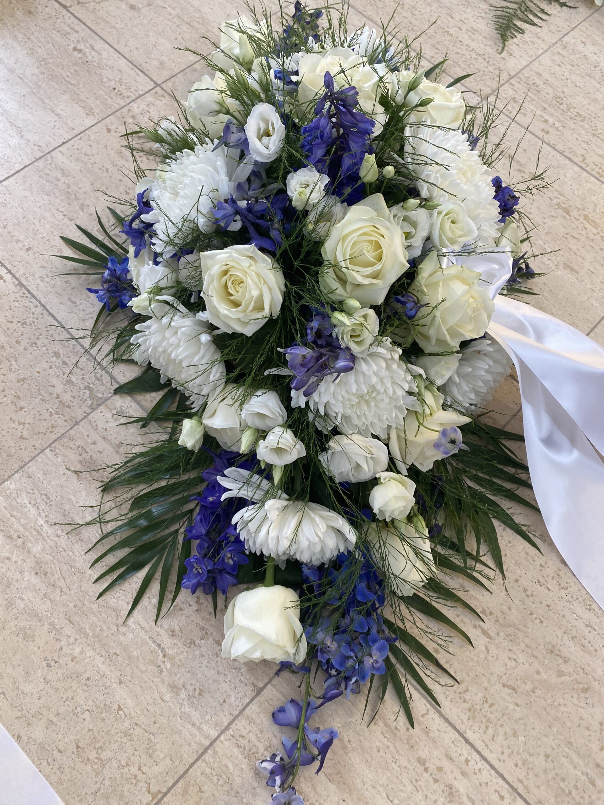Hvid og blå båredekoration med roser, chrysanthemum, ridderspore og hvidt bånd