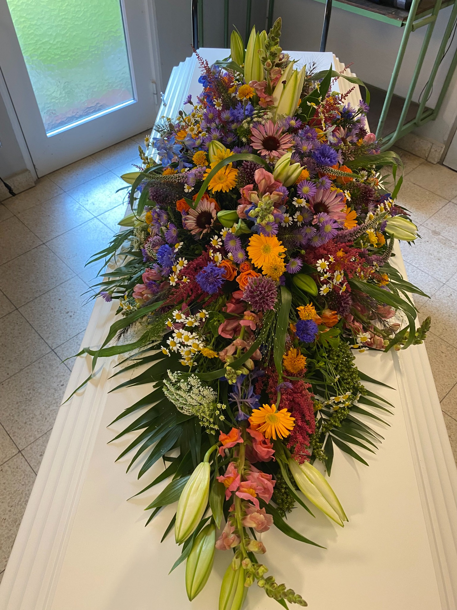 Farverig kistedekoration med orange, lilla og gule blomster
