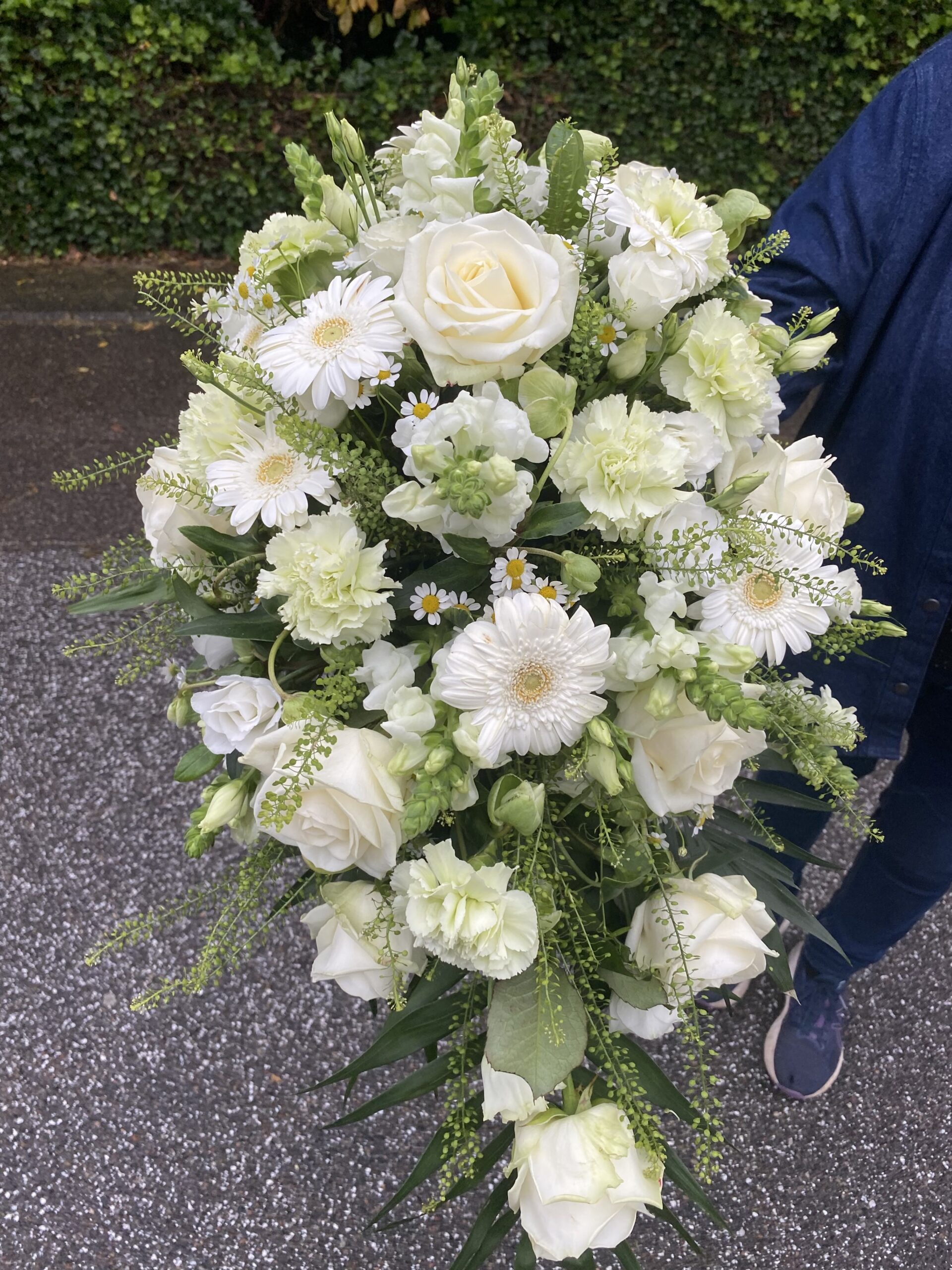 Hvid båredekoration med roser, gerbera, nelliker og løvemund