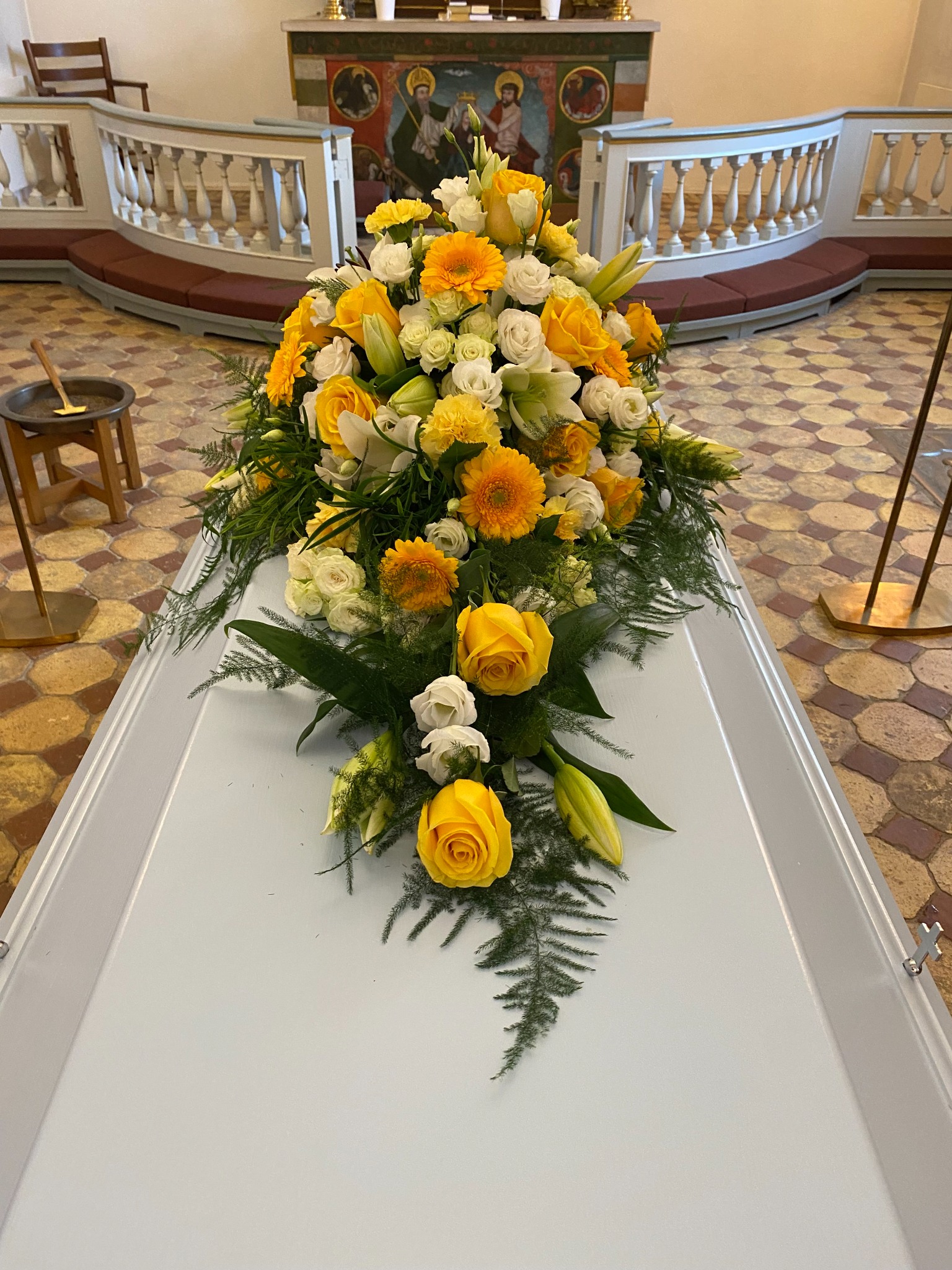 Kistedekoration med gule roser, hvide blomster og grønt