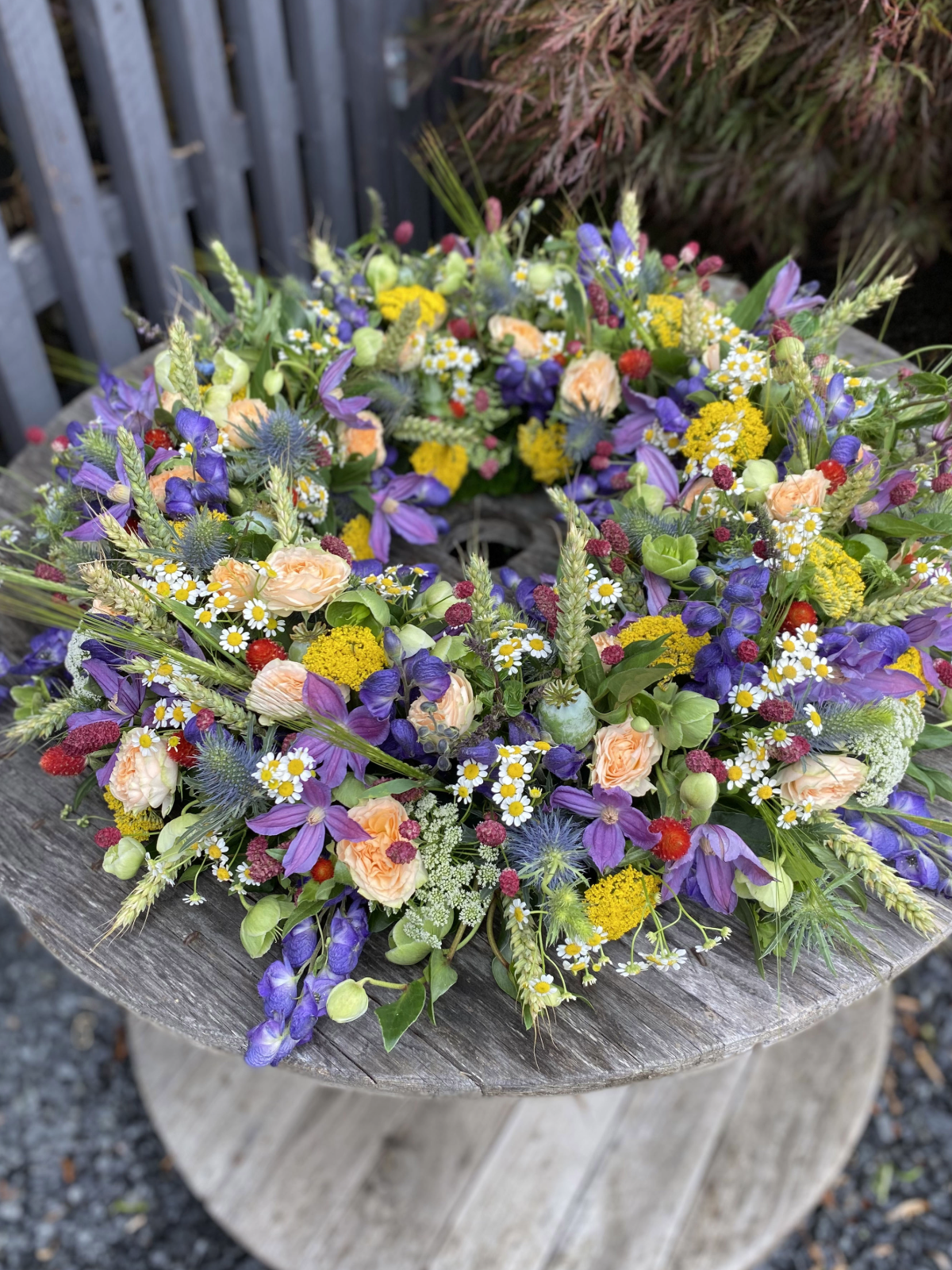 Farverig krans med markblomster, roser og korn.