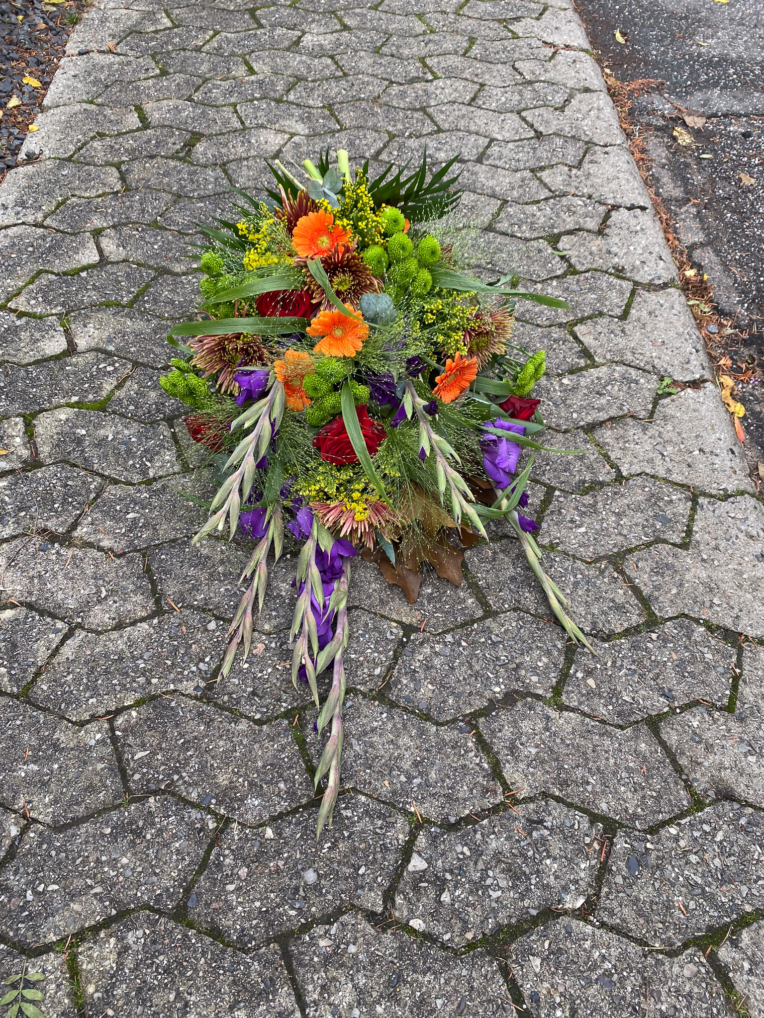 Bårebuket med orange gerbera, røde roser og lilla gladiolus