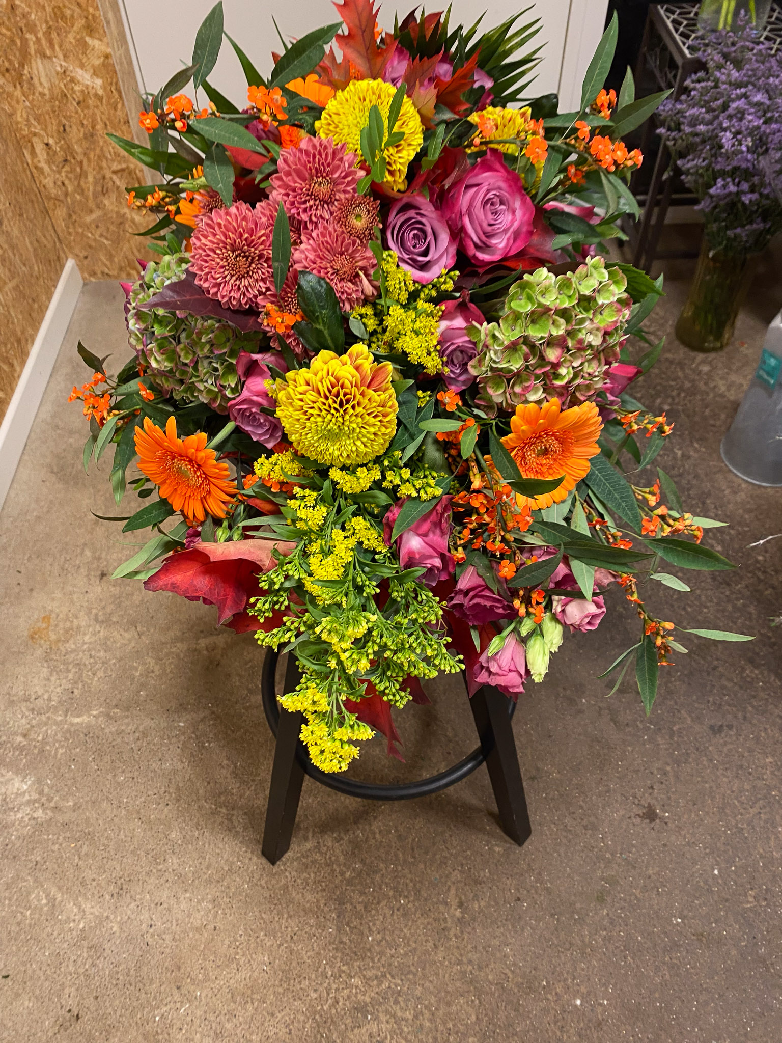 Bårebuket i høstfarver med lilla roser, orange gerbera, chrysanthemum og hortensia