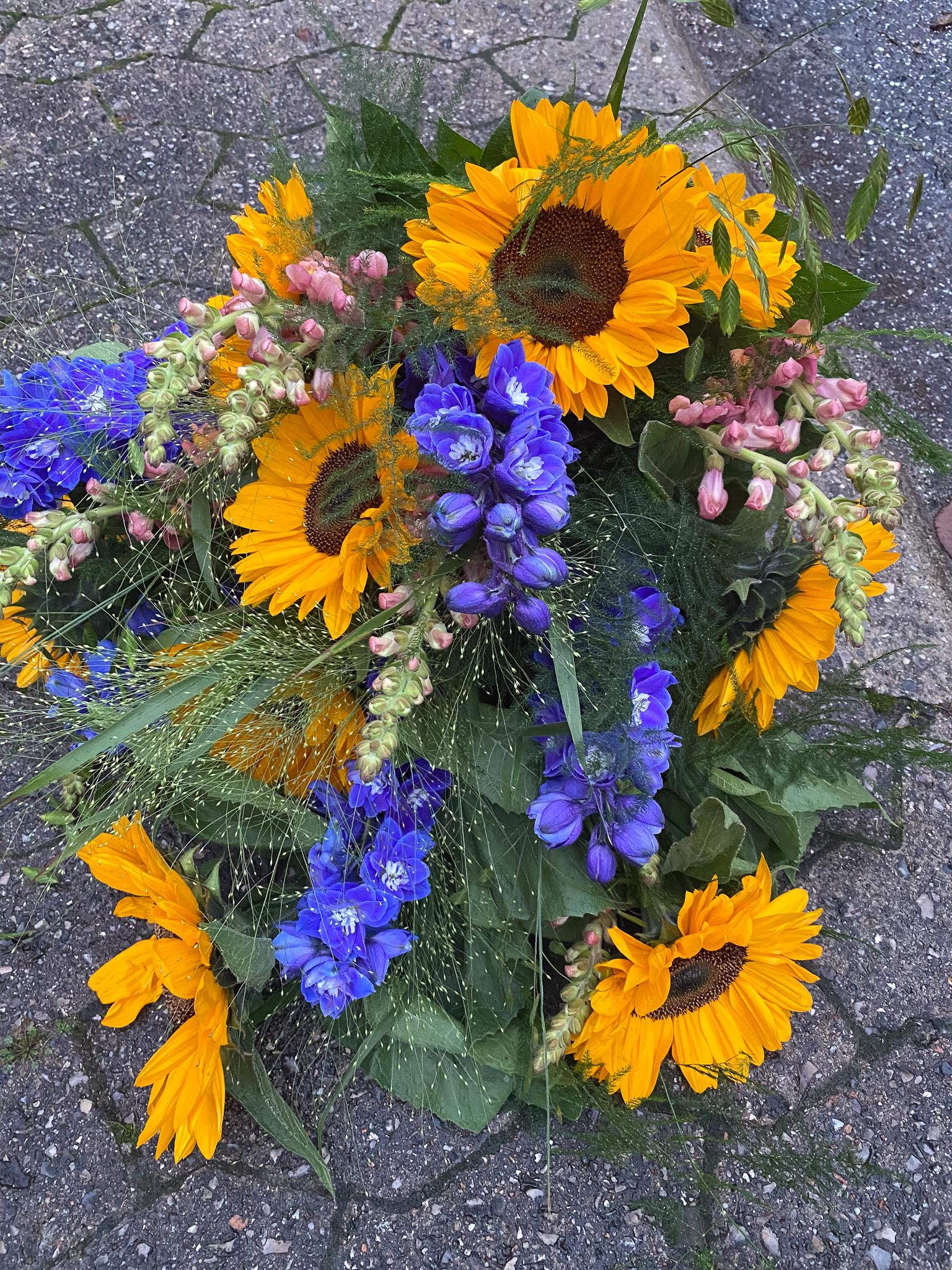 Bårebuket med solsikker, blå ridderspore og løvemund