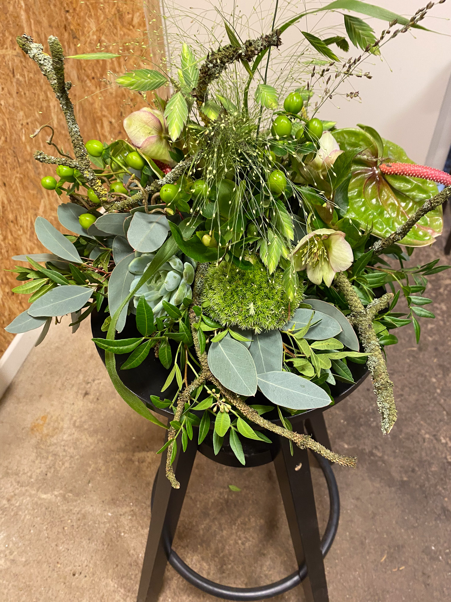 Grøn bårebuket med anthurium, julerose, hypericumbær og sukkulent